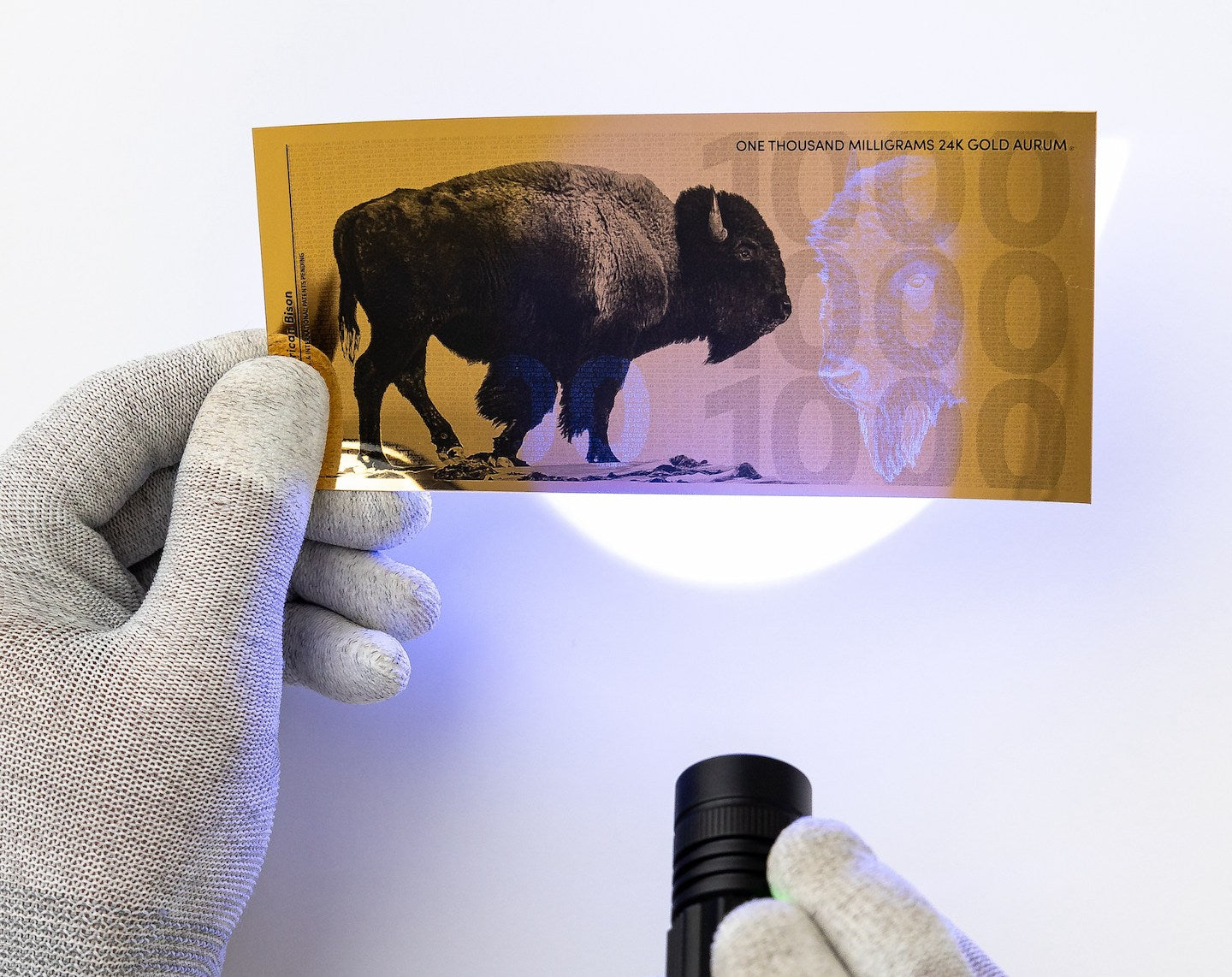 a blacklight held at the center of a one gram gold aurum bill revealing the hidden UV features