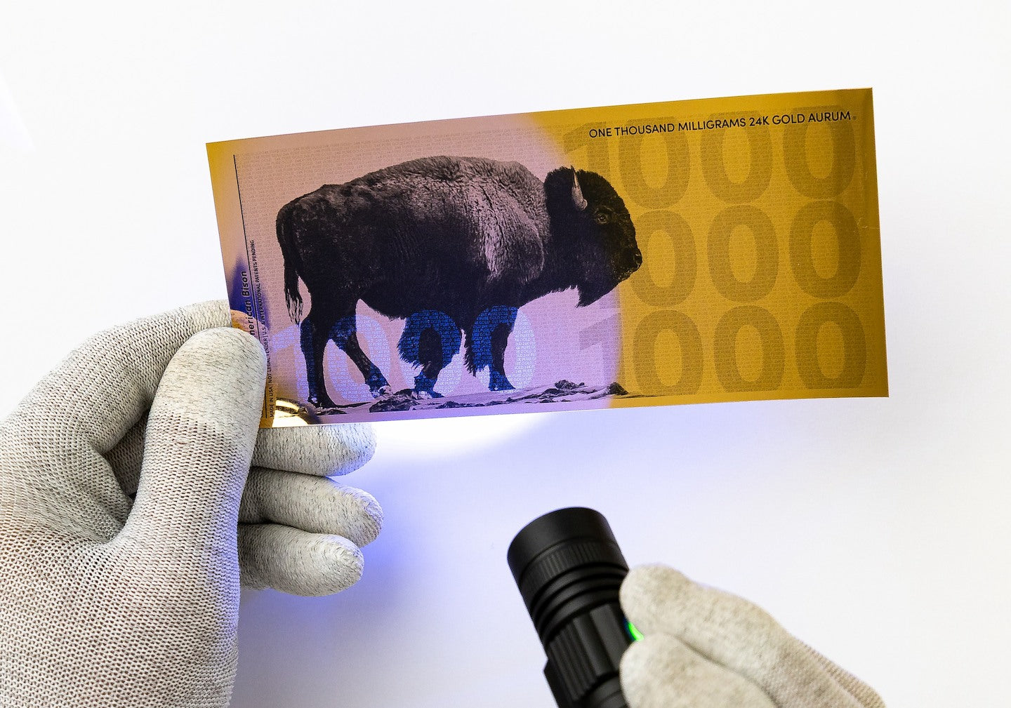 a blacklight held at the center of a one gram gold aurum bill revealing a hidden UV feature a 1000 showing at the bottom left